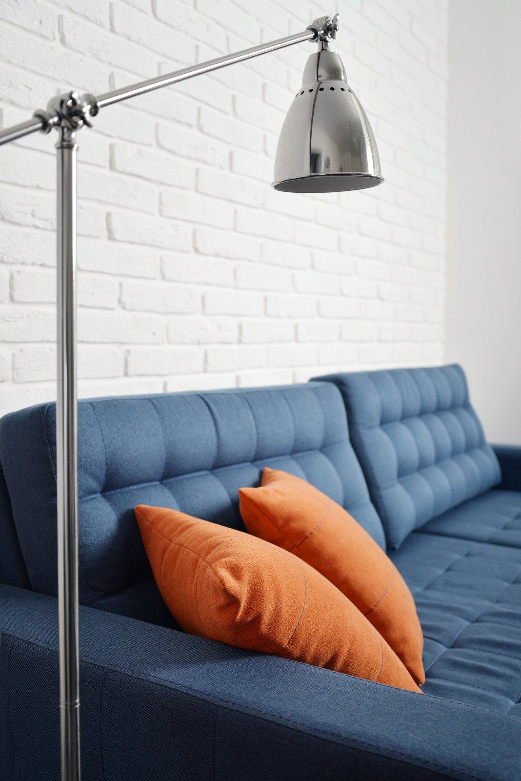 A blue couch with orange pillows and a lamp