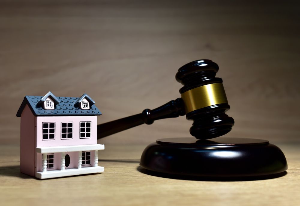 A small pink house is sitting next to a judge 's gavel on a wooden table.