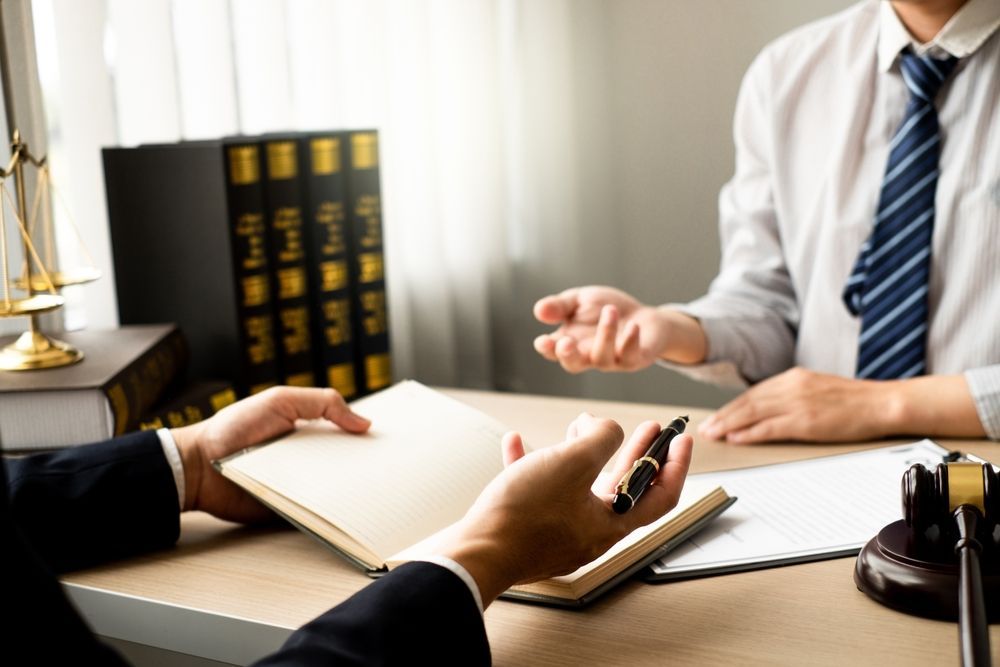 A lawyer is sitting at a desk talking to a client.