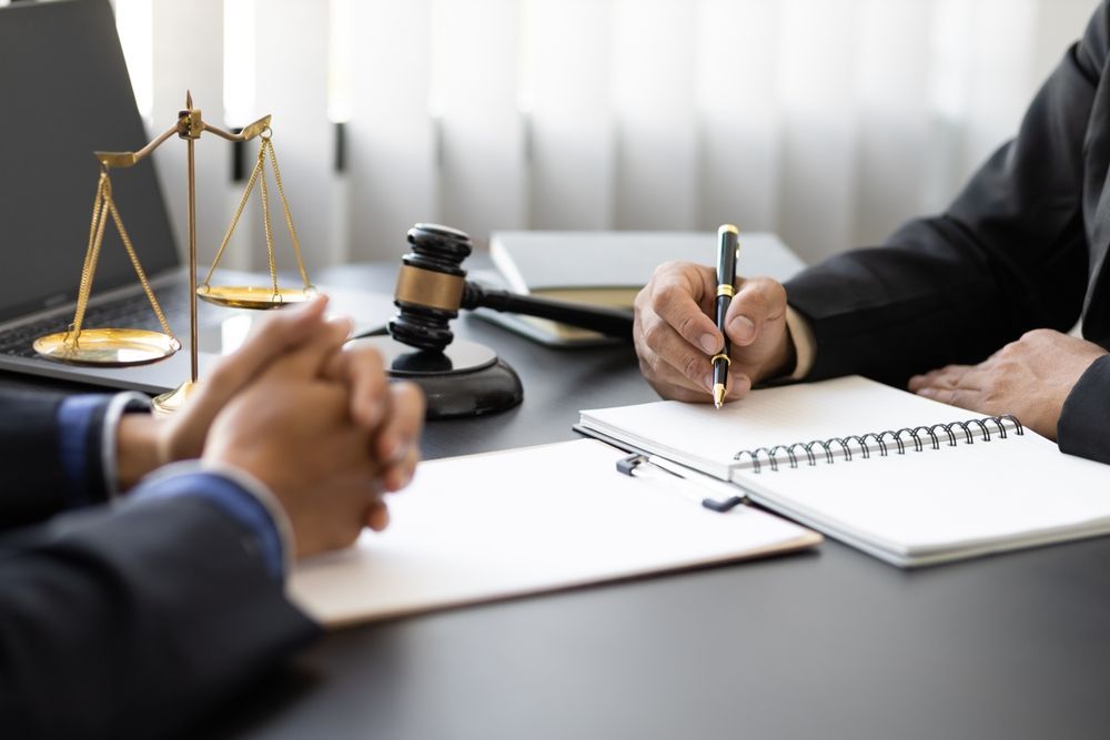 Two men are sitting at a table with a judge 's gavel and a notebook.