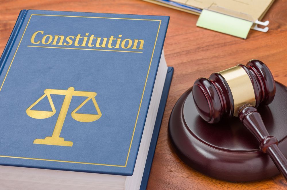 A blue book titled constitution sits on a wooden table next to a judge 's gavel