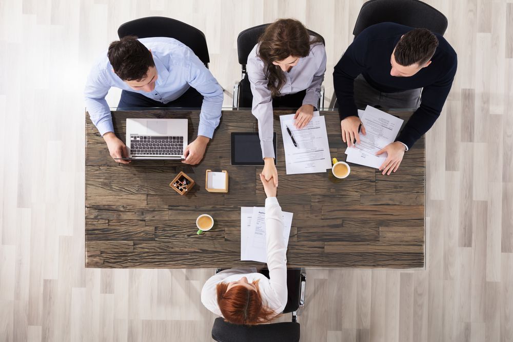 A group of people are sitting at a table shaking hands.