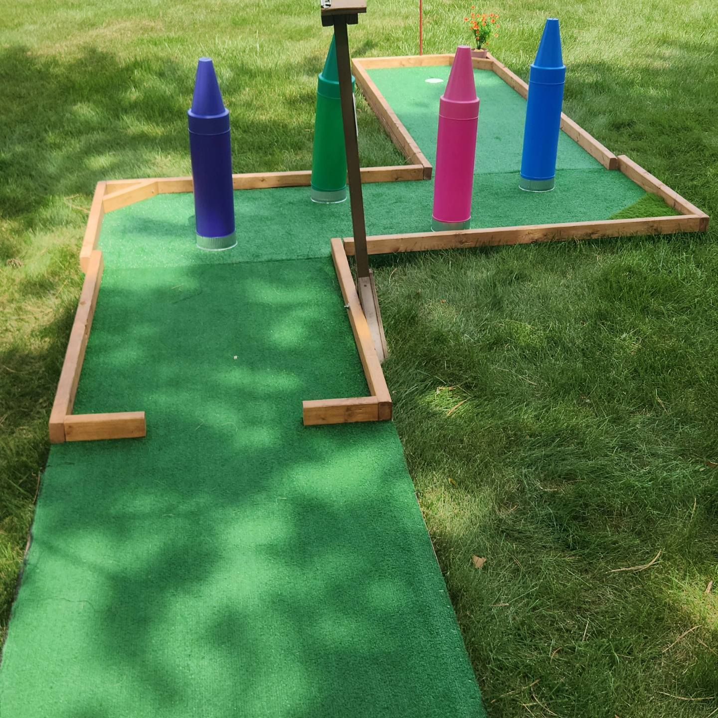 Miniature golf course with crayon-shaped obstacles in a grassy yard.