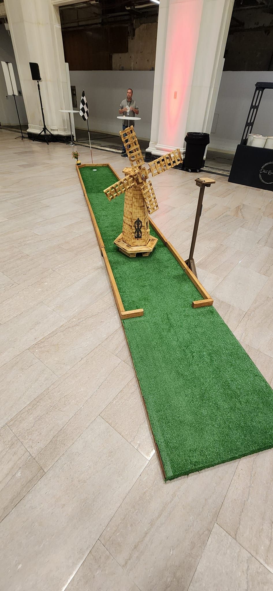 Miniature golf course with wooden obstacles on green turf, indoors.
