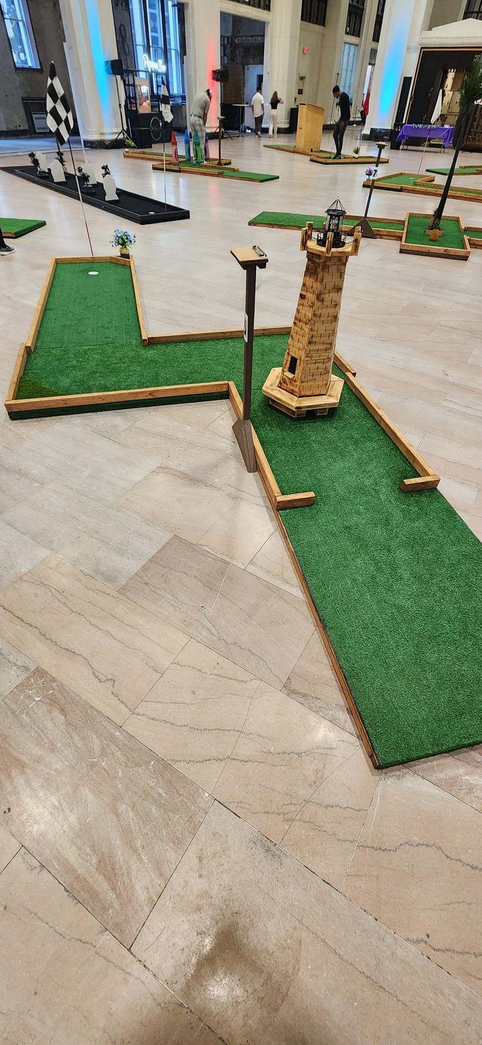 Mini golf course with a lighthouse obstacle indoors.