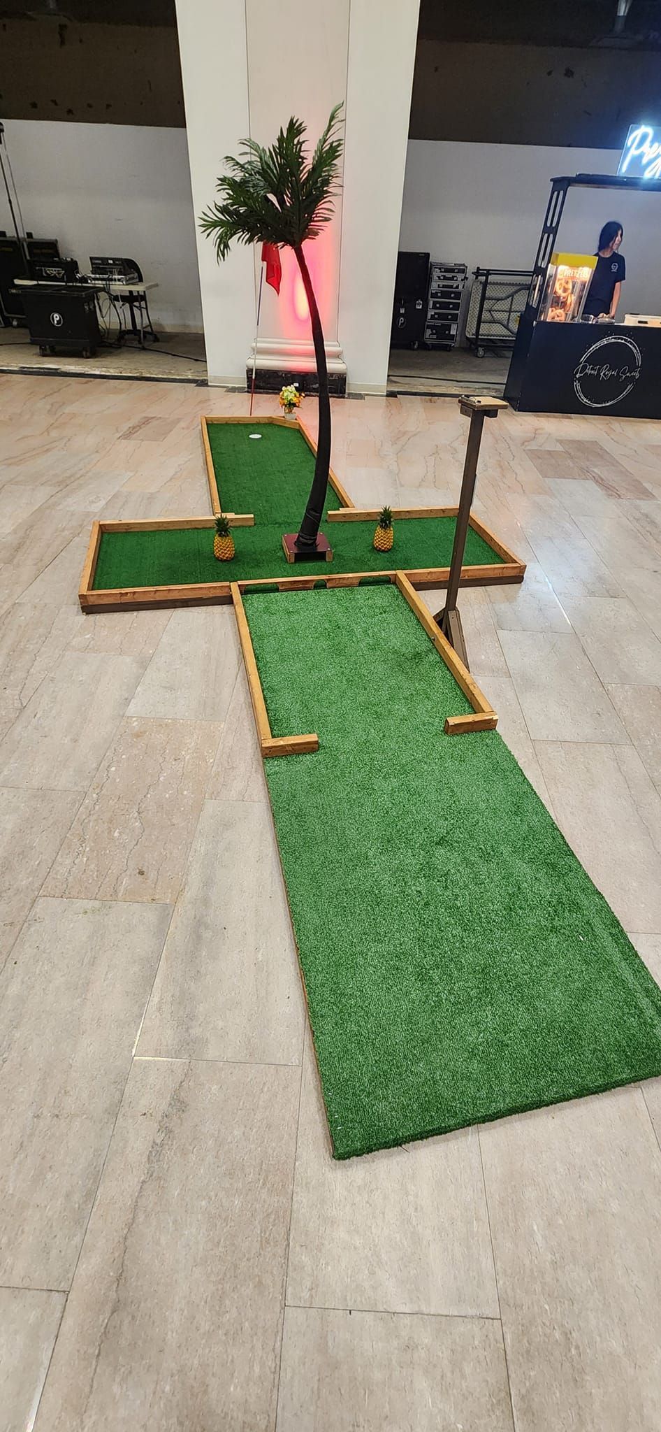 Miniature golf course on a concrete floor, a small tree is in the center.