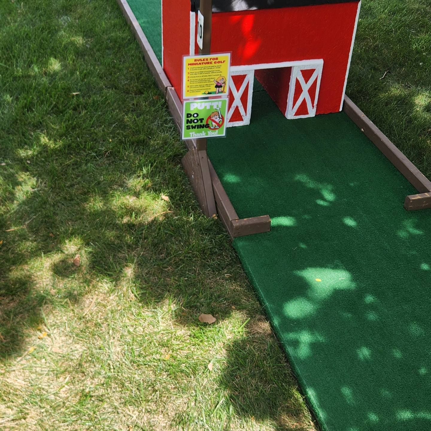 Miniature golf course hole with a red barn feature.