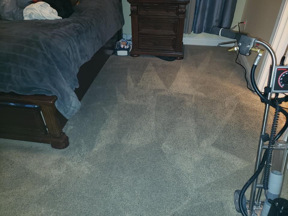A bedroom with a bed and nightstand and a vacuum on the floor