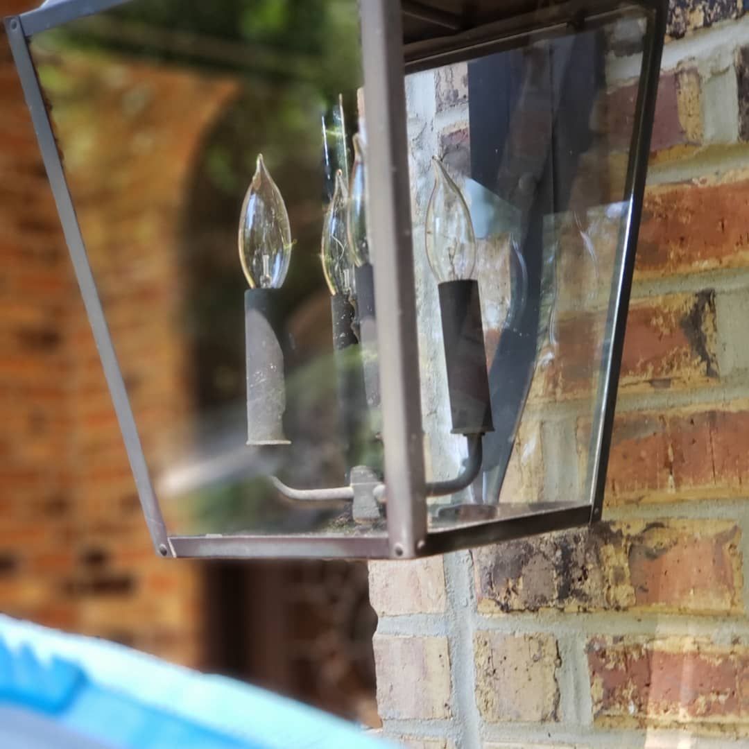 A lantern hanging on a brick wall with candles inside