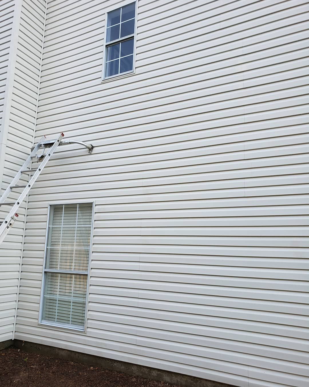 A white house with a ladder attached to the side of it.