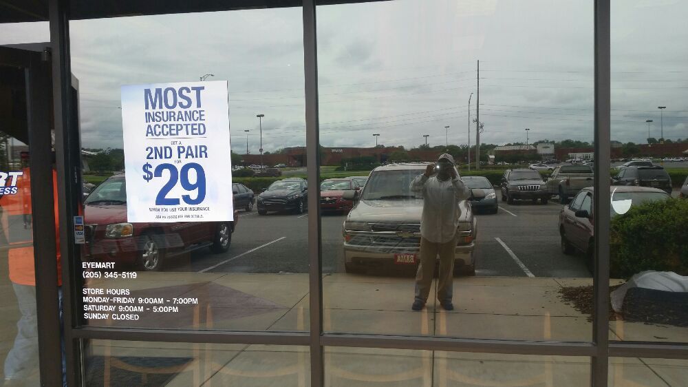 A man is taking a picture of a parking lot with a sign that says most accepted 2nd pair $ 29