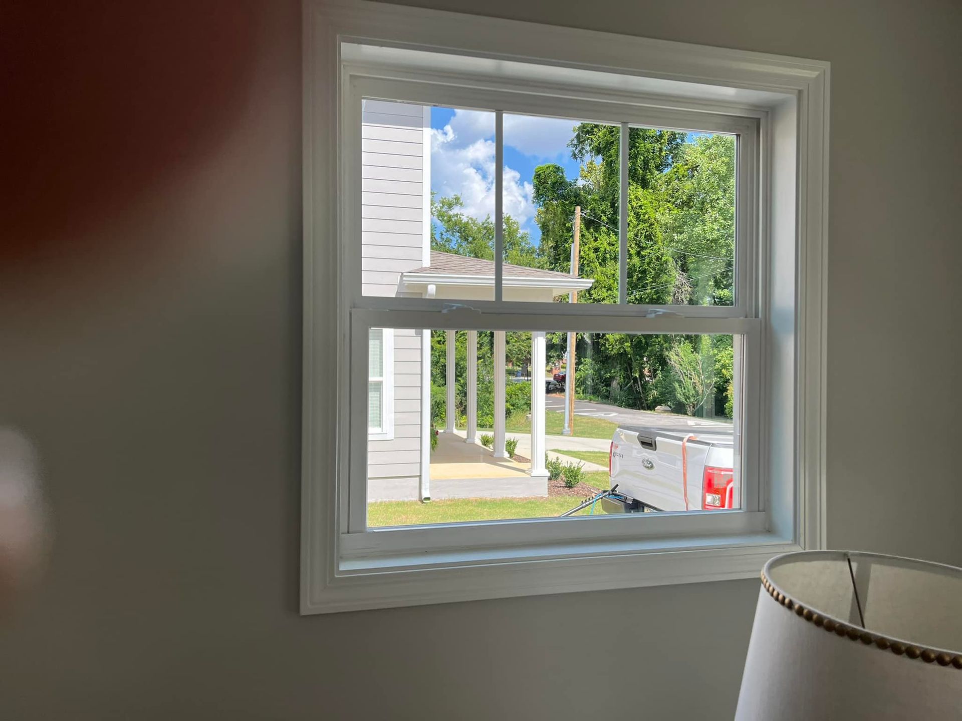 A window in a room with a lamp and a view of a house.
