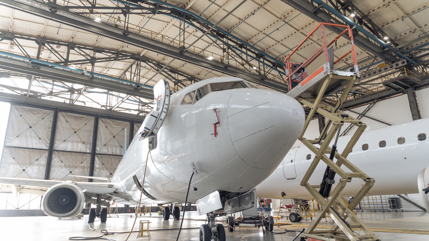 An airplane is being worked on in a hangar with a scissor lift.