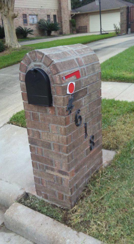 Brick mailbox with black mailbox, address numbers, and raised red flag.