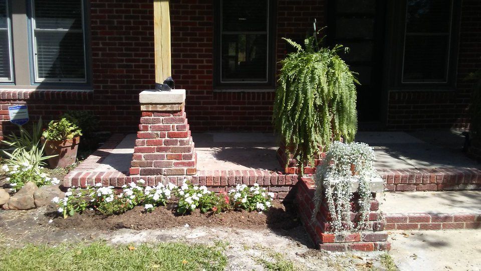 Brick wall with missing brick; wood frame; sliding glass door, and hanging plant.