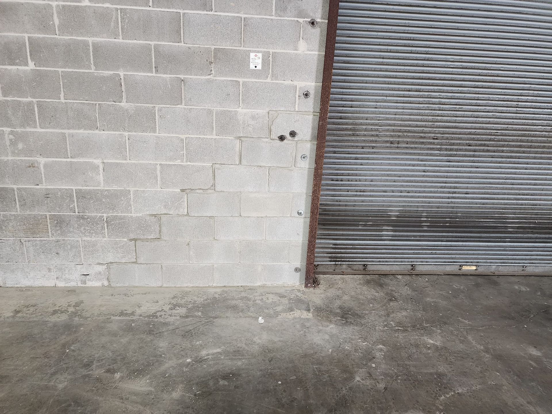 Gray cinder block wall and metal security gate. Concrete floor.