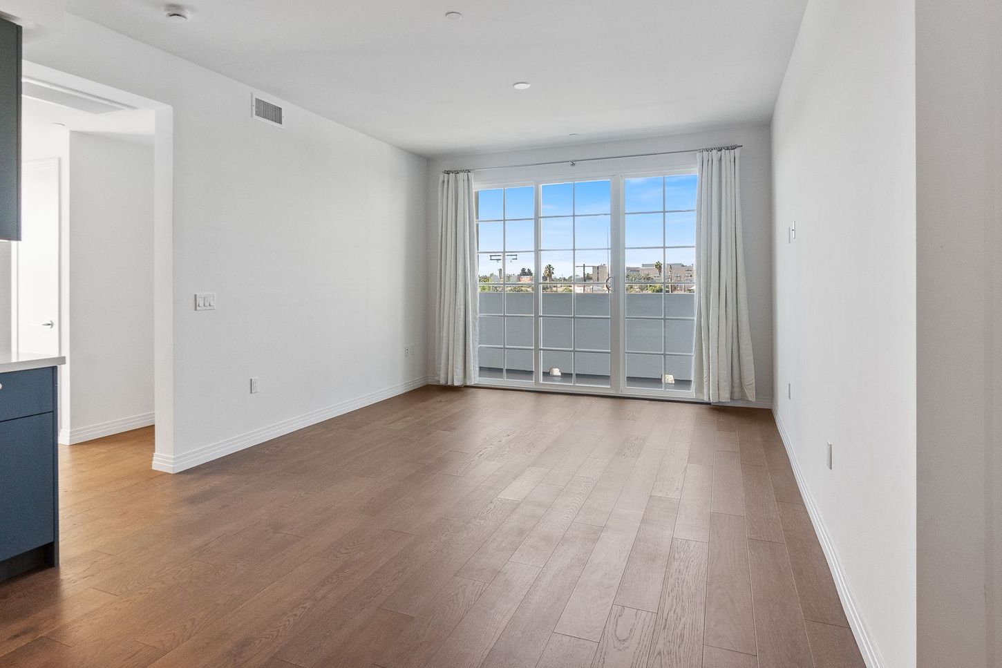 An empty living room with hardwood floors and sliding glass doors