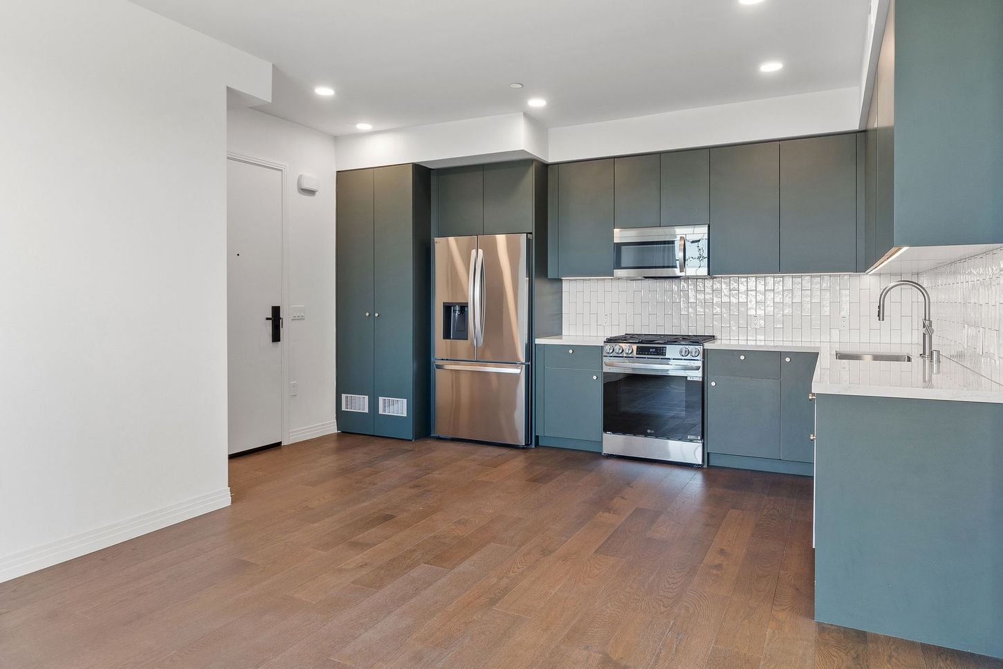 A kitchen with stainless steel appliances and wooden floors.