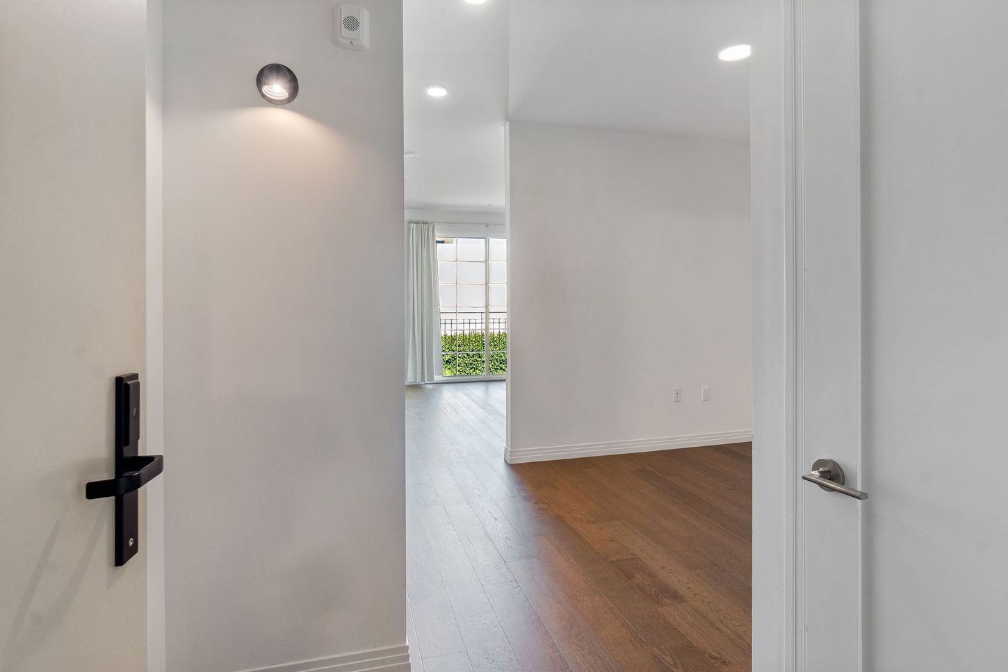 A hallway in a house with a wooden floor and white walls.