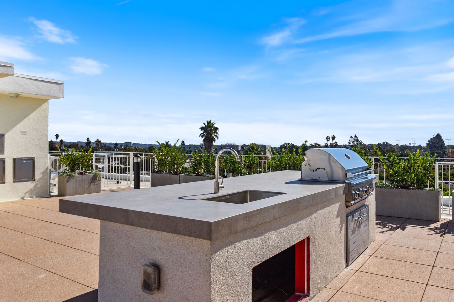 A rooftop kitchen with a grill and sink