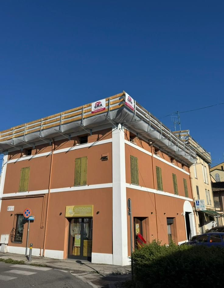 Due edifici a più piani in costruzione, con impalcature esterne, si stagliano contro un cielo azzurro con nuvole sparse.