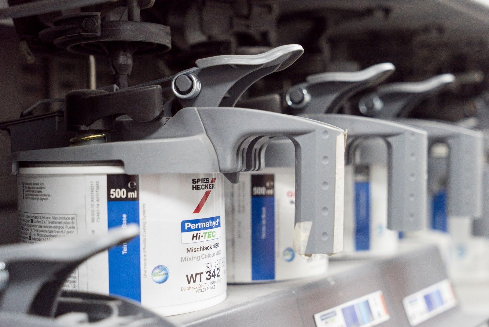 Una fila di contenitori di vernice sono allineati su uno scaffale.