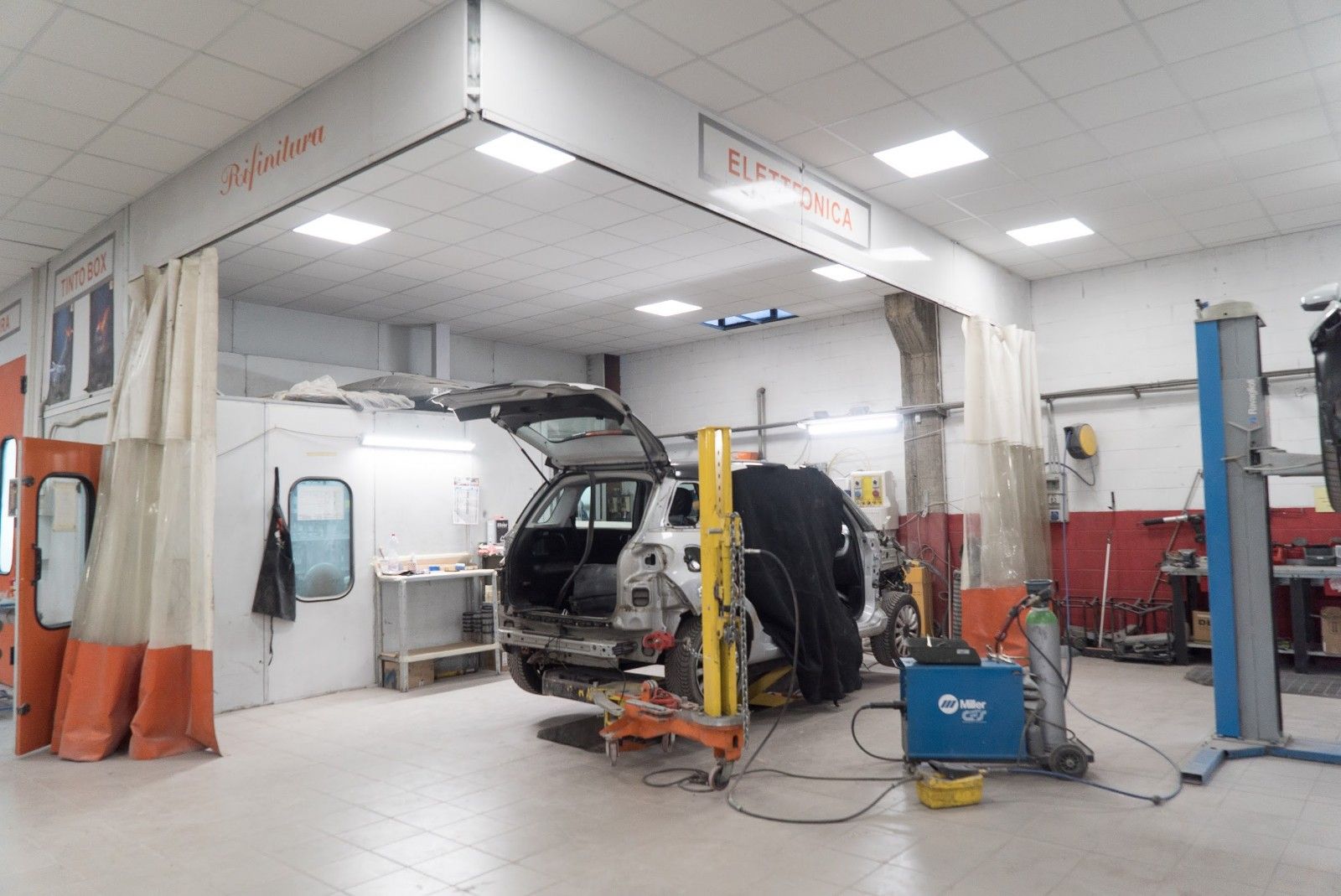 Un'auto è parcheggiata su un ponte sollevatore in un garage.