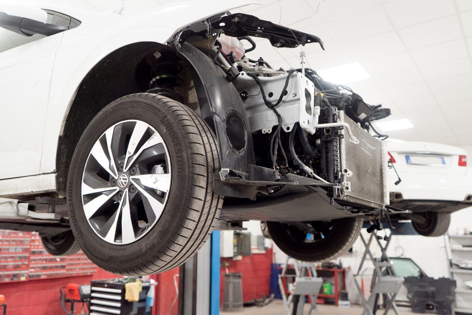 Un'auto bianca viene riparata su un ponte sollevatore in un garage.