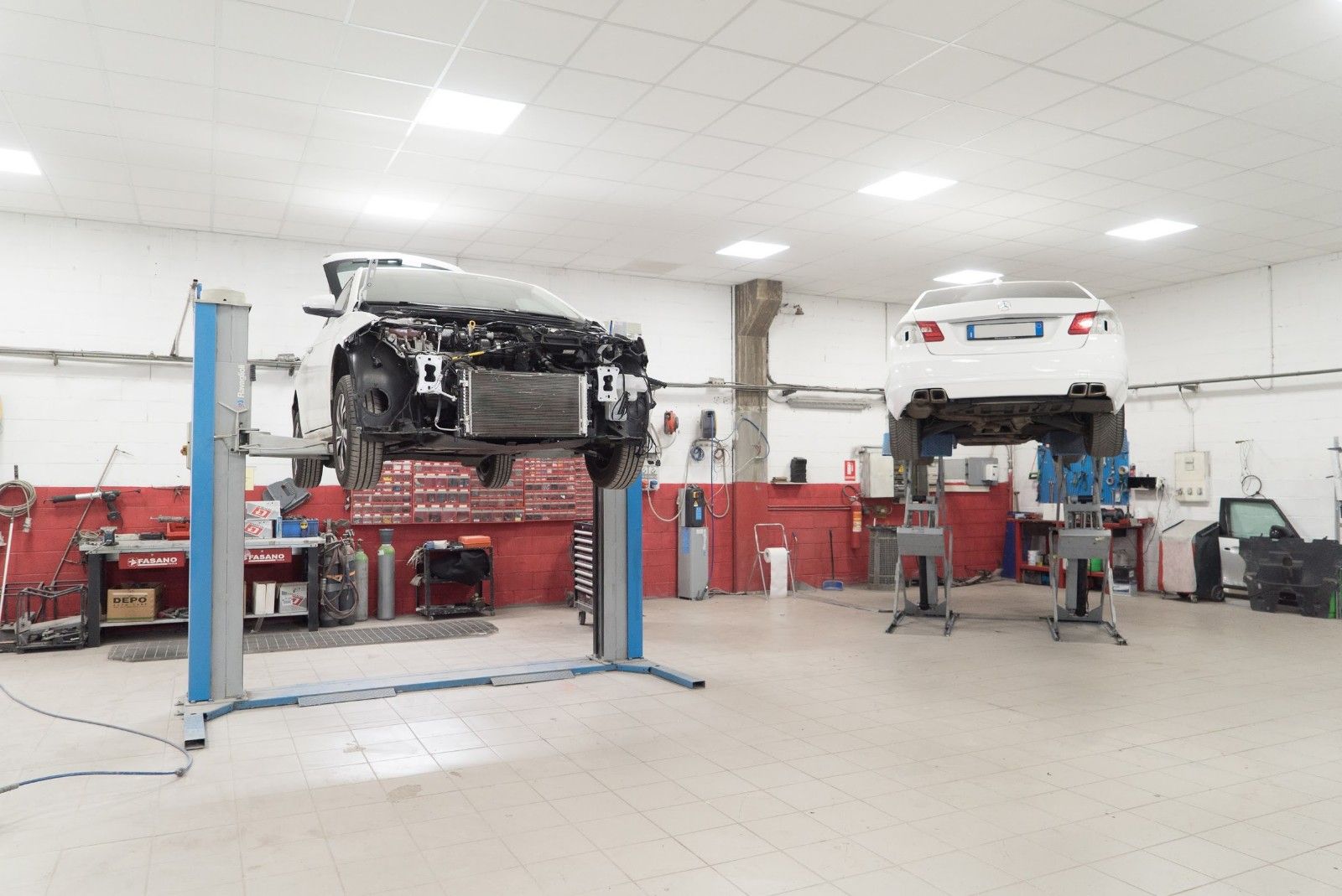Due auto sono parcheggiate su un sollevatore in un garage.