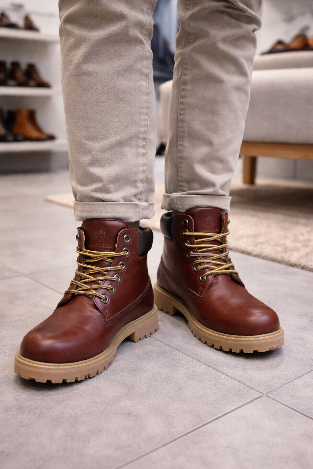 Persona che indossa stivali da lavoro in pelle marrone e pantaloni color cuoio in un negozio di scarpe.