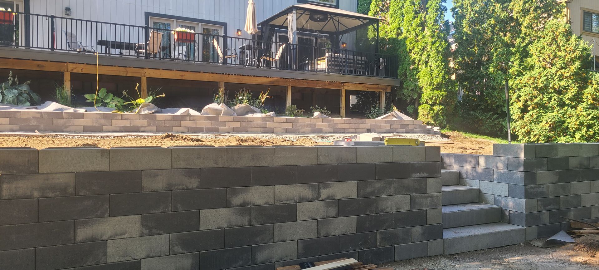 Concrete block retaining wall with steps leading up to a deck and backyard.