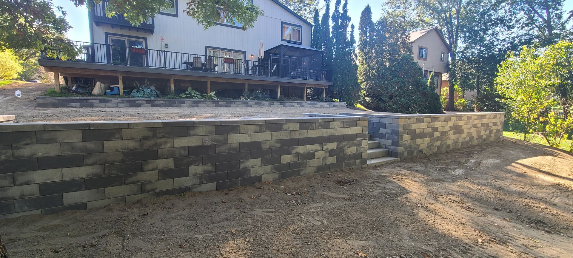 A multi-level backyard with a retaining wall, steps, and a house in the background.