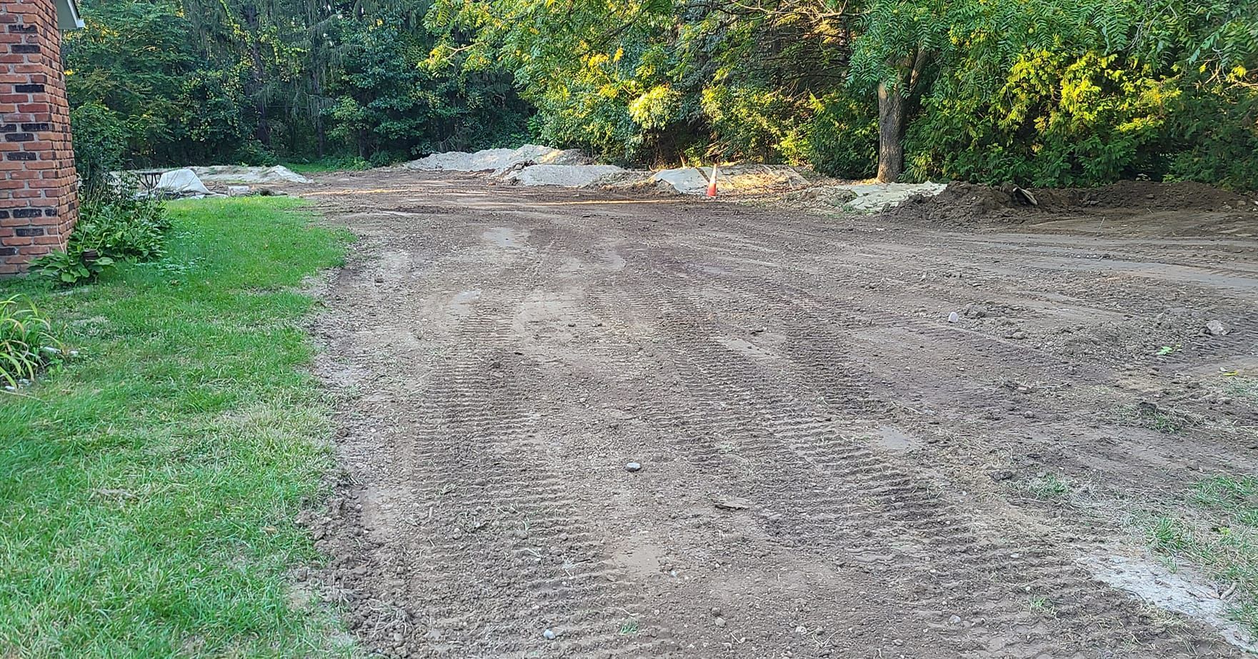 A dirt road leading to a brick building with a brick wall in the background.