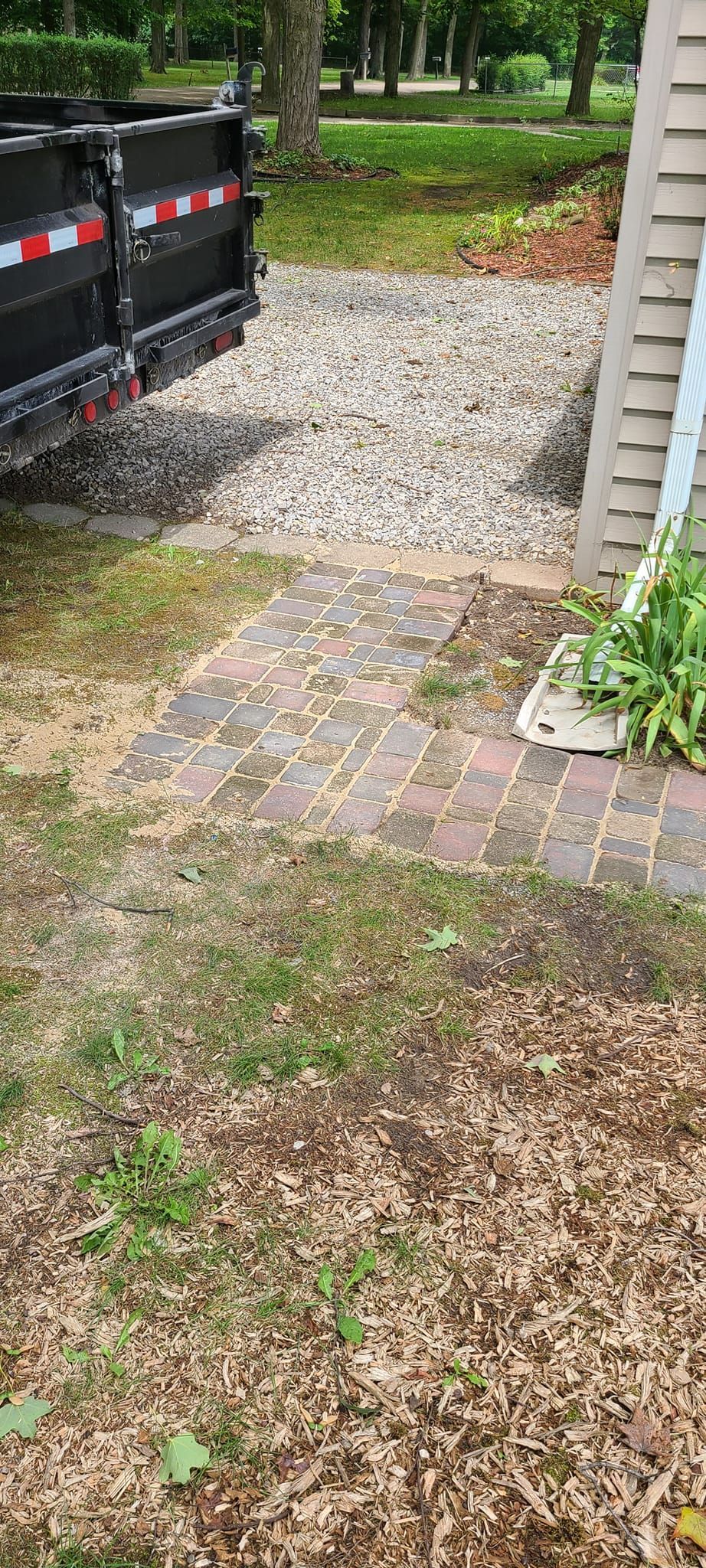 A dump truck is parked in a yard next to a brick walkway.