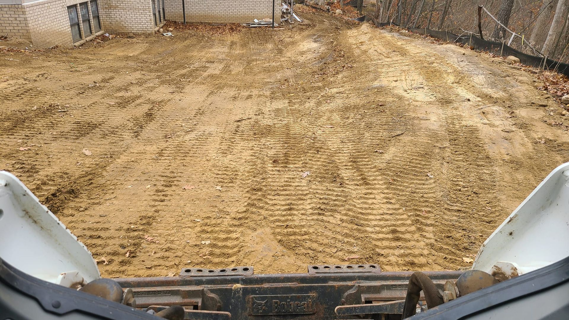 A bulldozer is clearing a dirt field in front of a house.