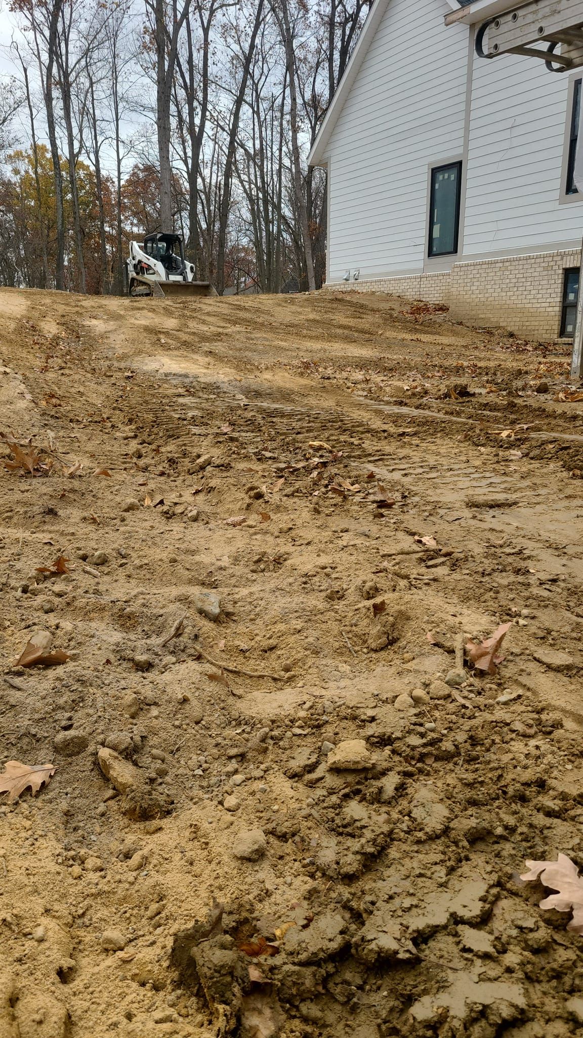 A person is standing in a pile of dirt in front of a house.