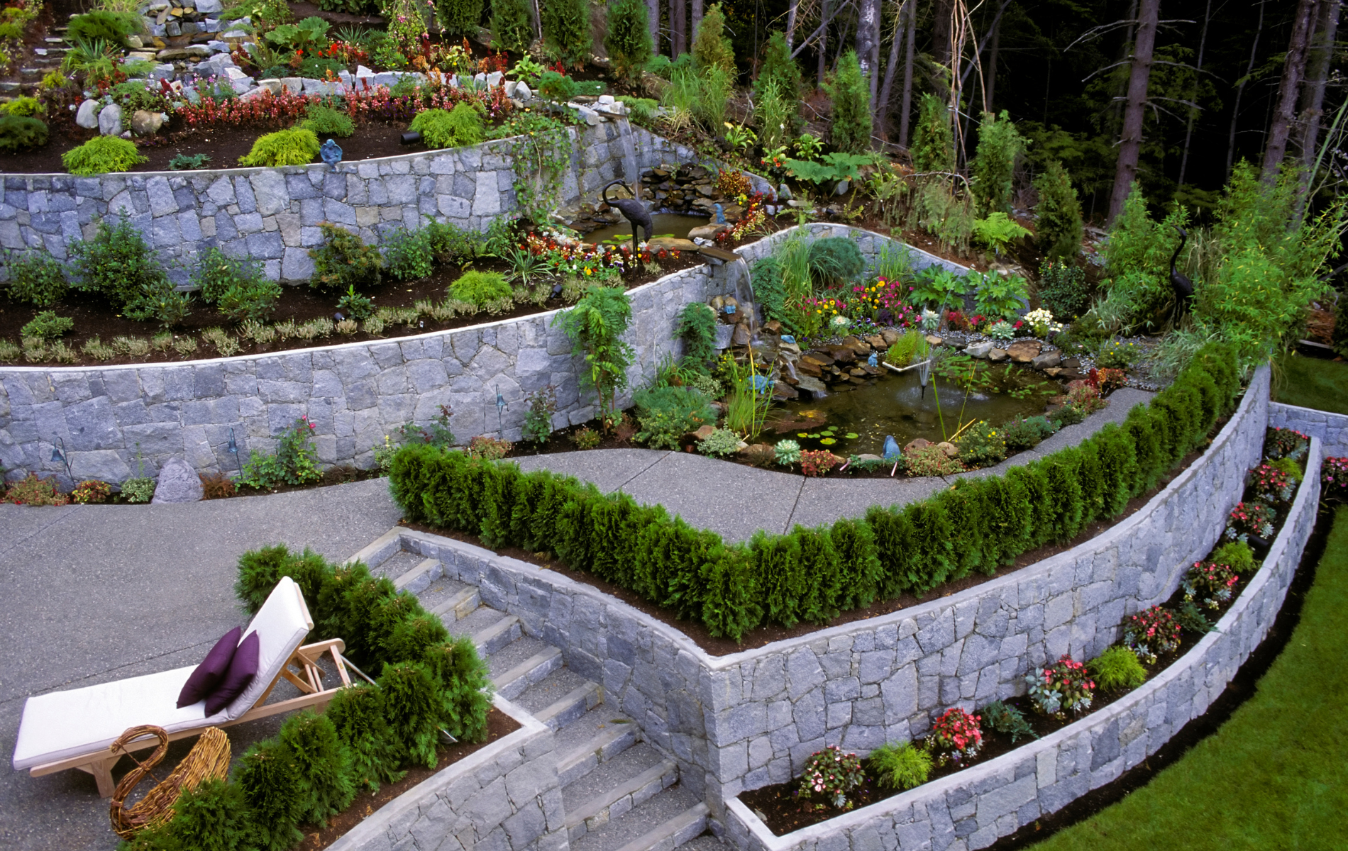 A lush green garden with a stone wall and stairs