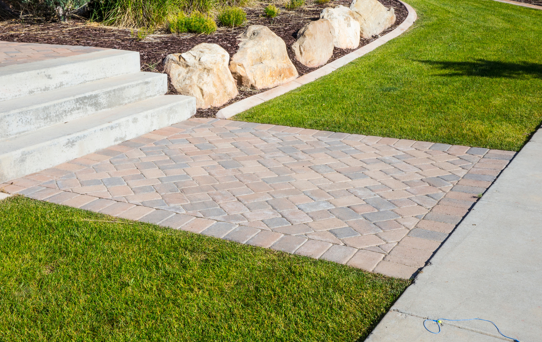 A brick walkway leading to a lush green lawn.