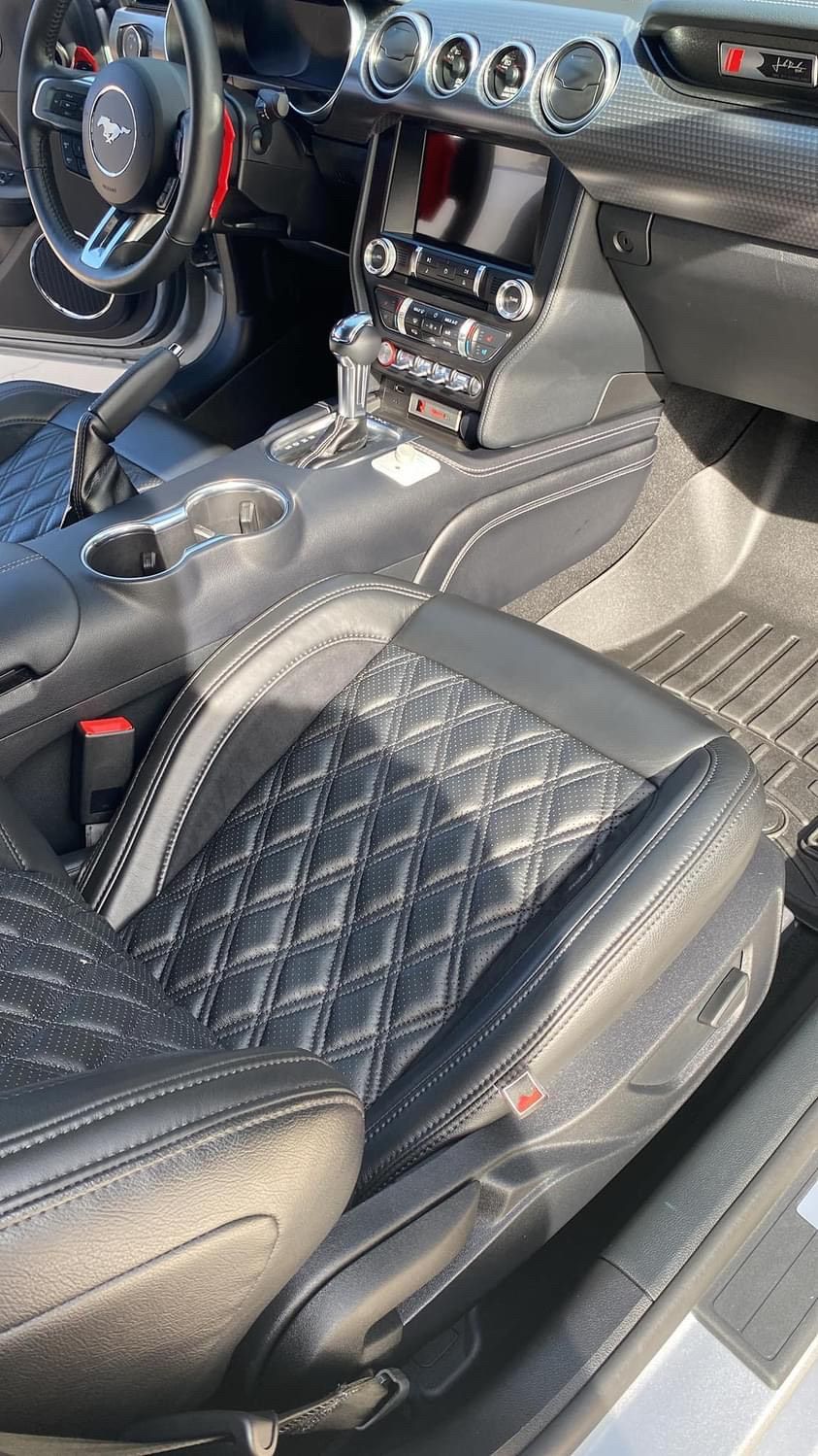 The interior of a ford mustang with black leather seats and a steering wheel.
