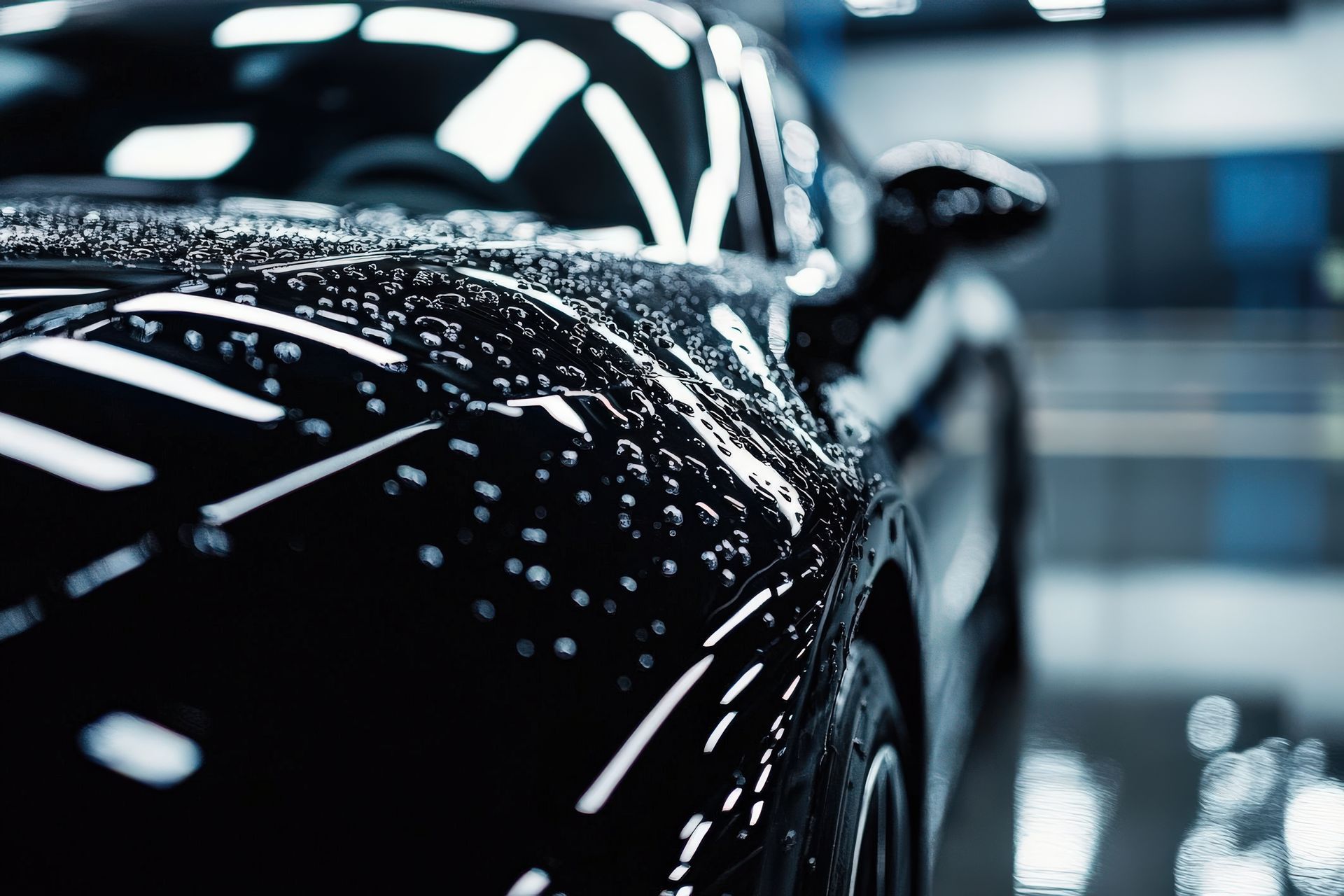 A close up of a black car with water drops on the hood.
