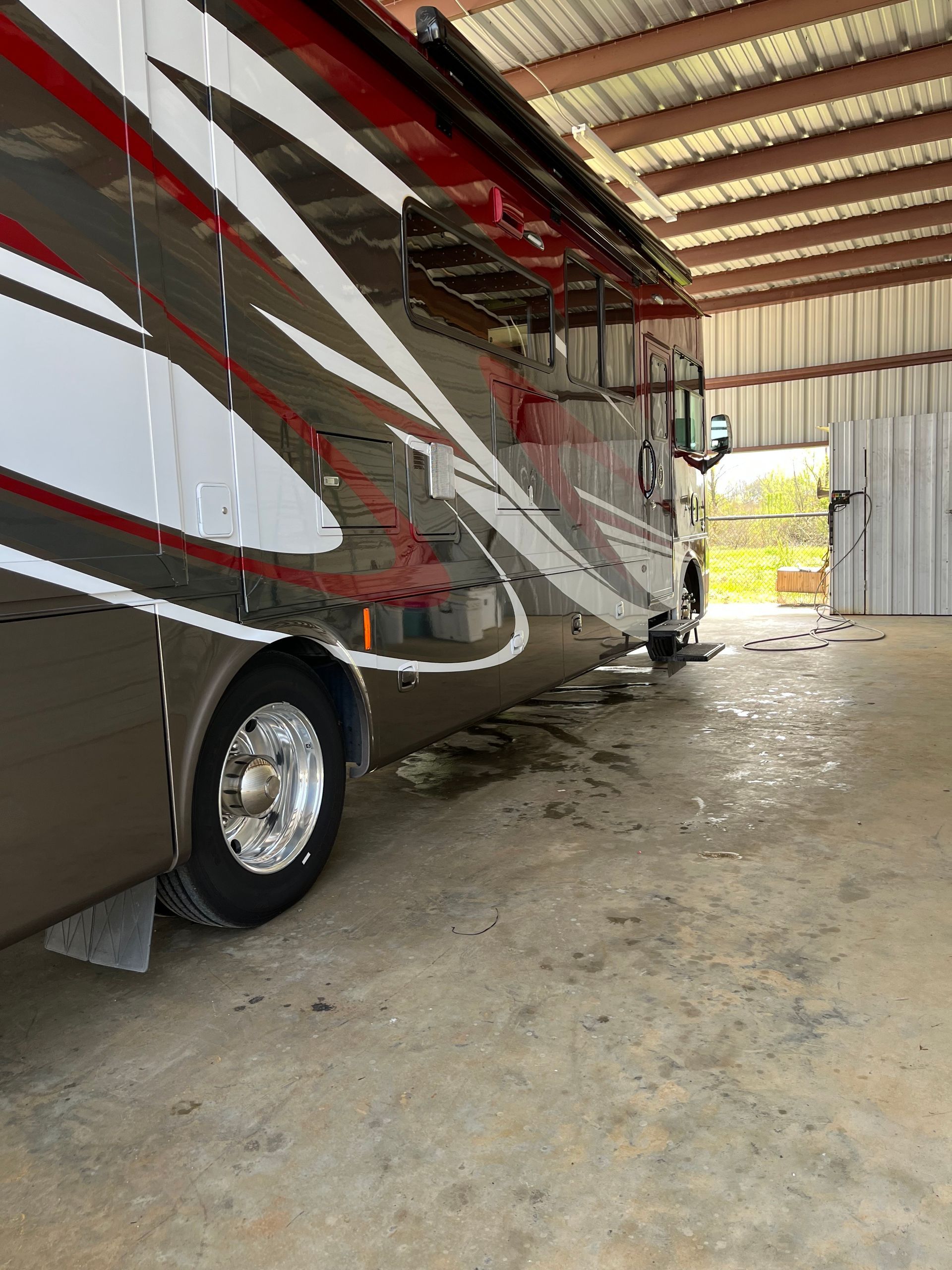 Two rvs are parked in a garage under a roof