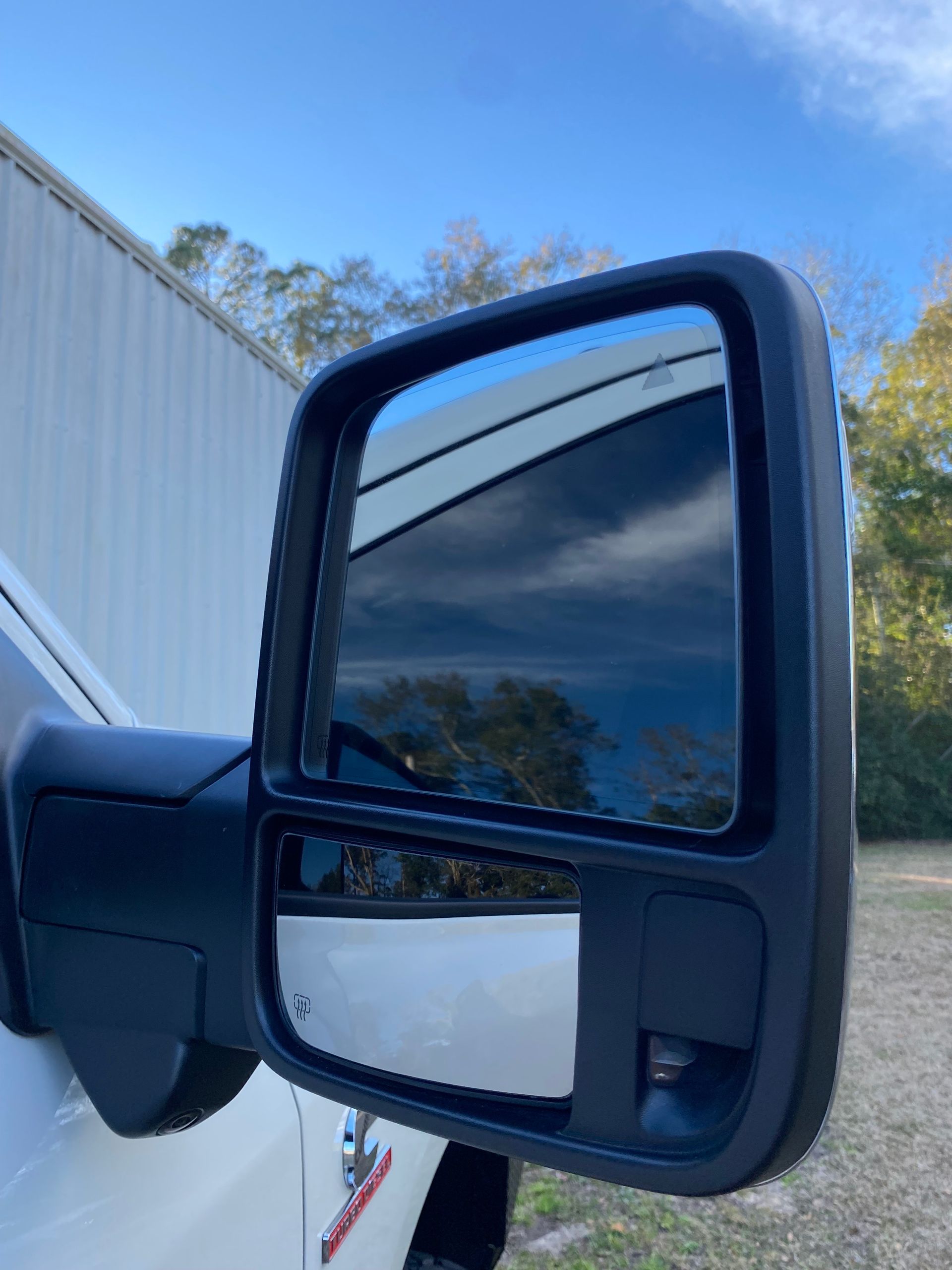 A close up of a side view mirror on a white truck