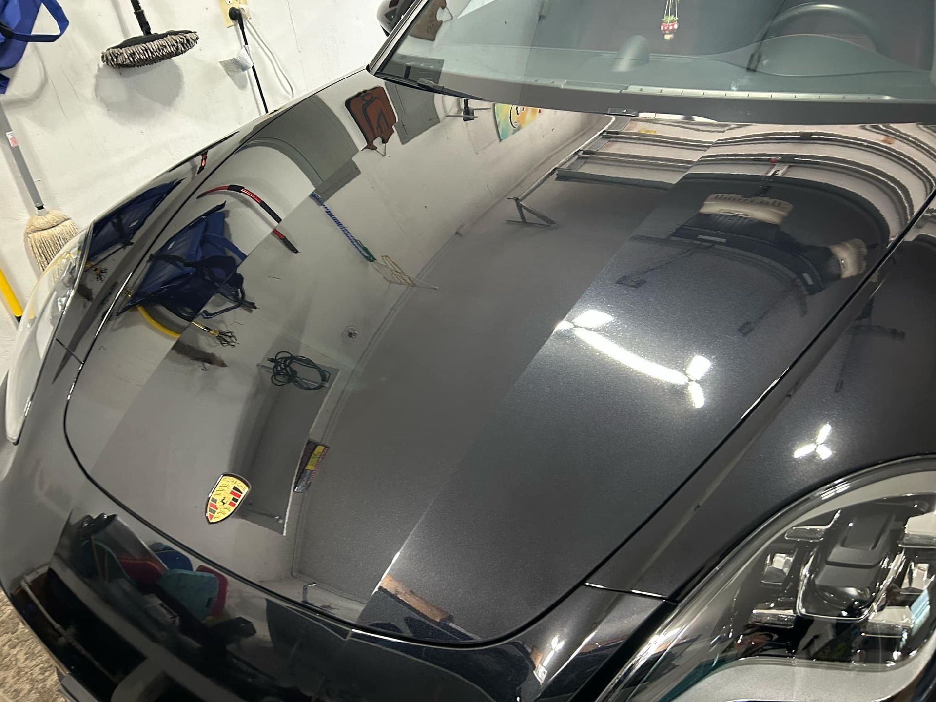 A black car is parked in a garage with the hood up.