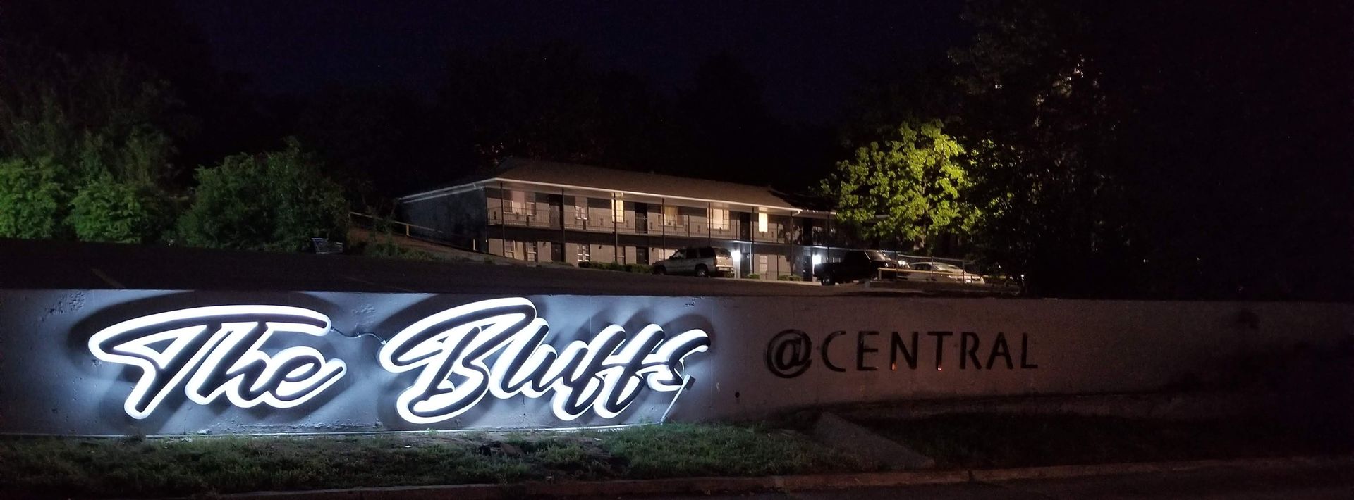 Nighttime sign reading “The Bluff” in glowing script beside “Central” on a dark wall