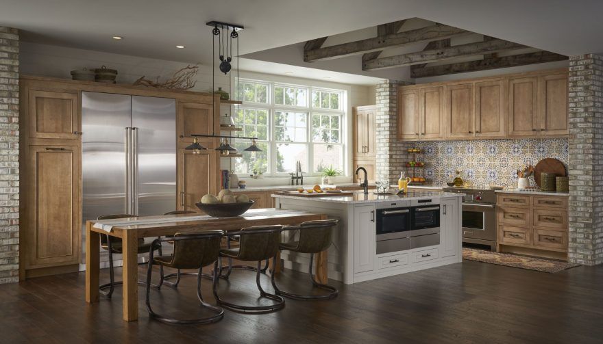 A kitchen with wooden cabinets , stainless steel appliances , a table and chairs.
