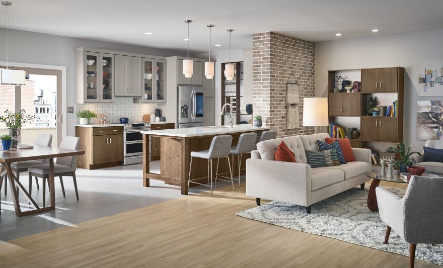 A living room with a couch , chairs , a table and a kitchen.