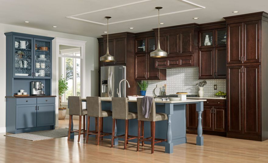 A kitchen with a large island , stools and a refrigerator.