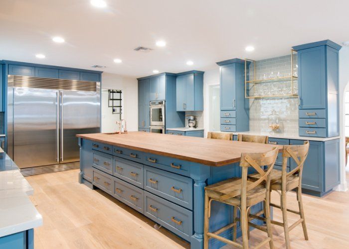 A kitchen with blue cabinets , stainless steel appliances , and a large island.