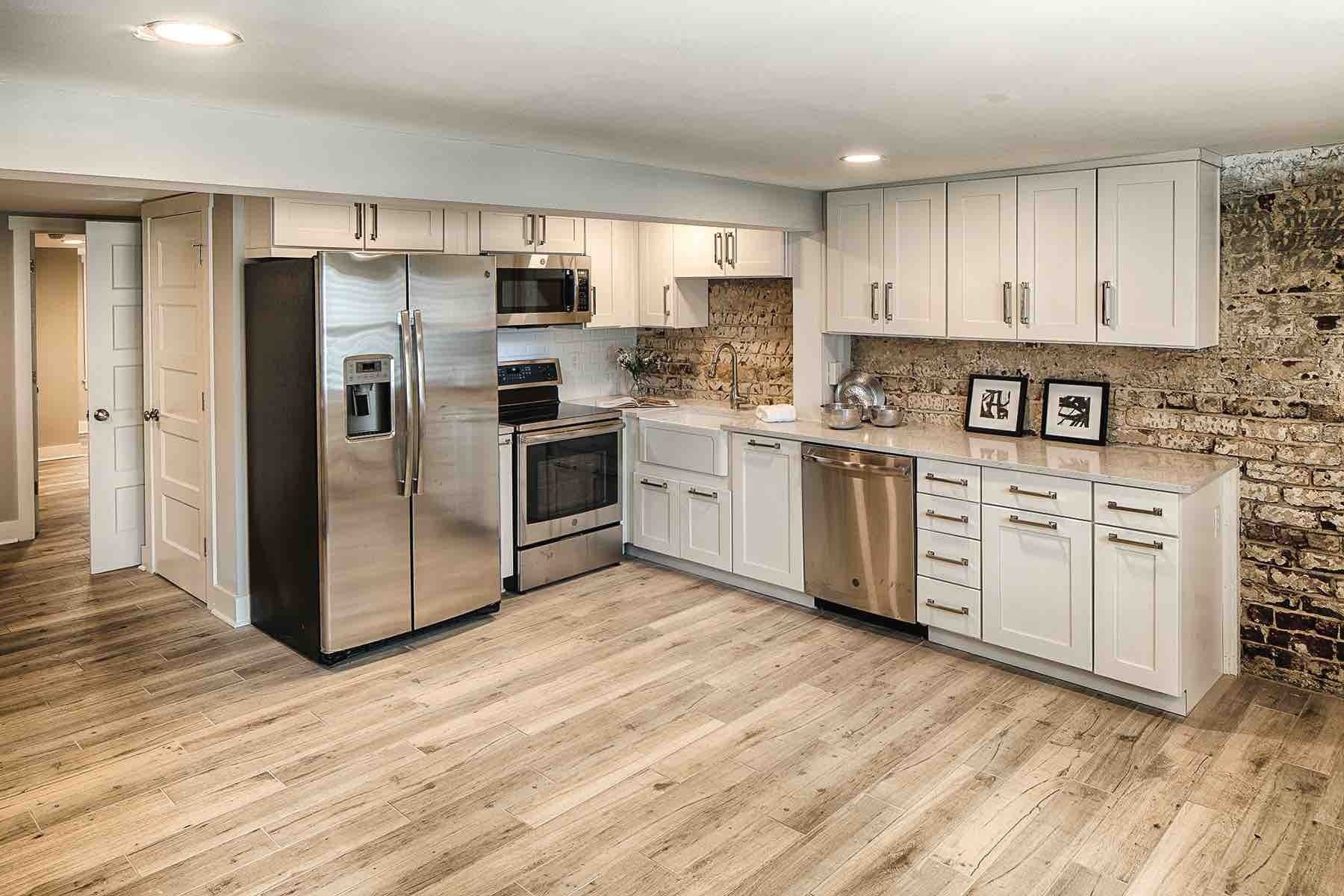 A kitchen in a basement with stainless steel appliances and white cabinets.