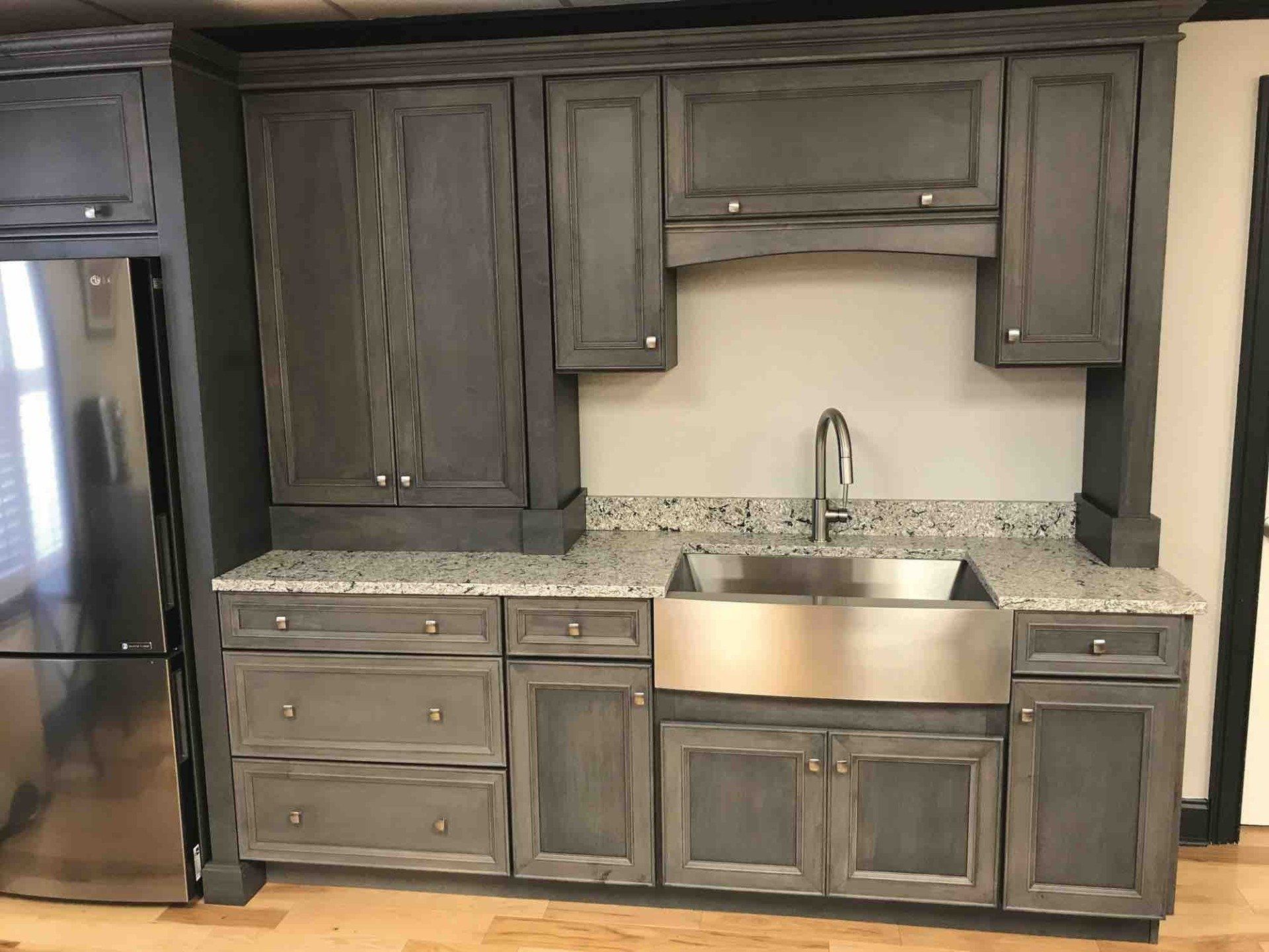 A kitchen with gray cabinets and a stainless steel sink.
